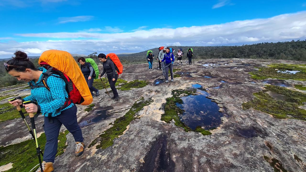 women hiking up gentle rock incline
