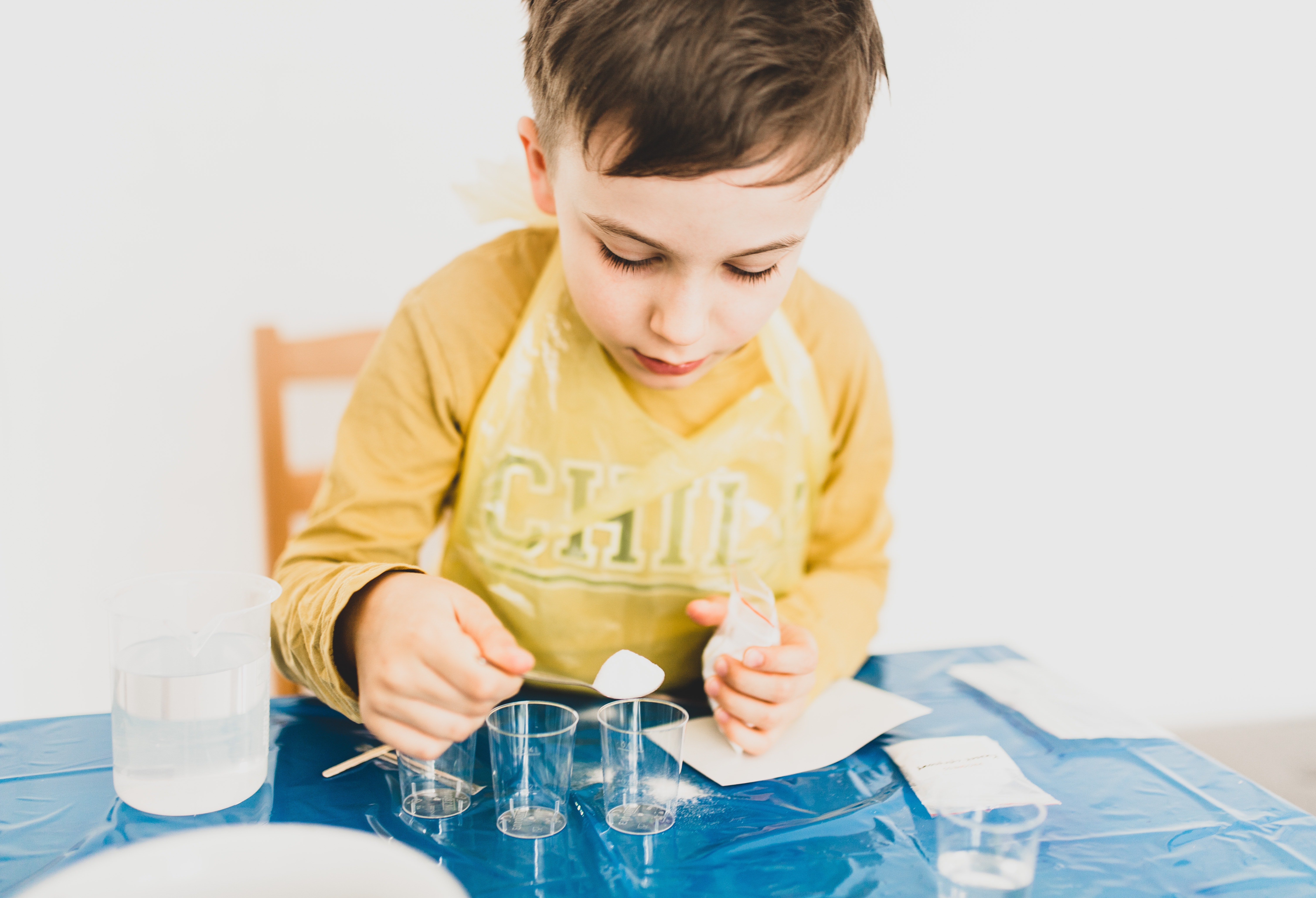 primary aged boy mixing powder into measuring beakers for an experiment