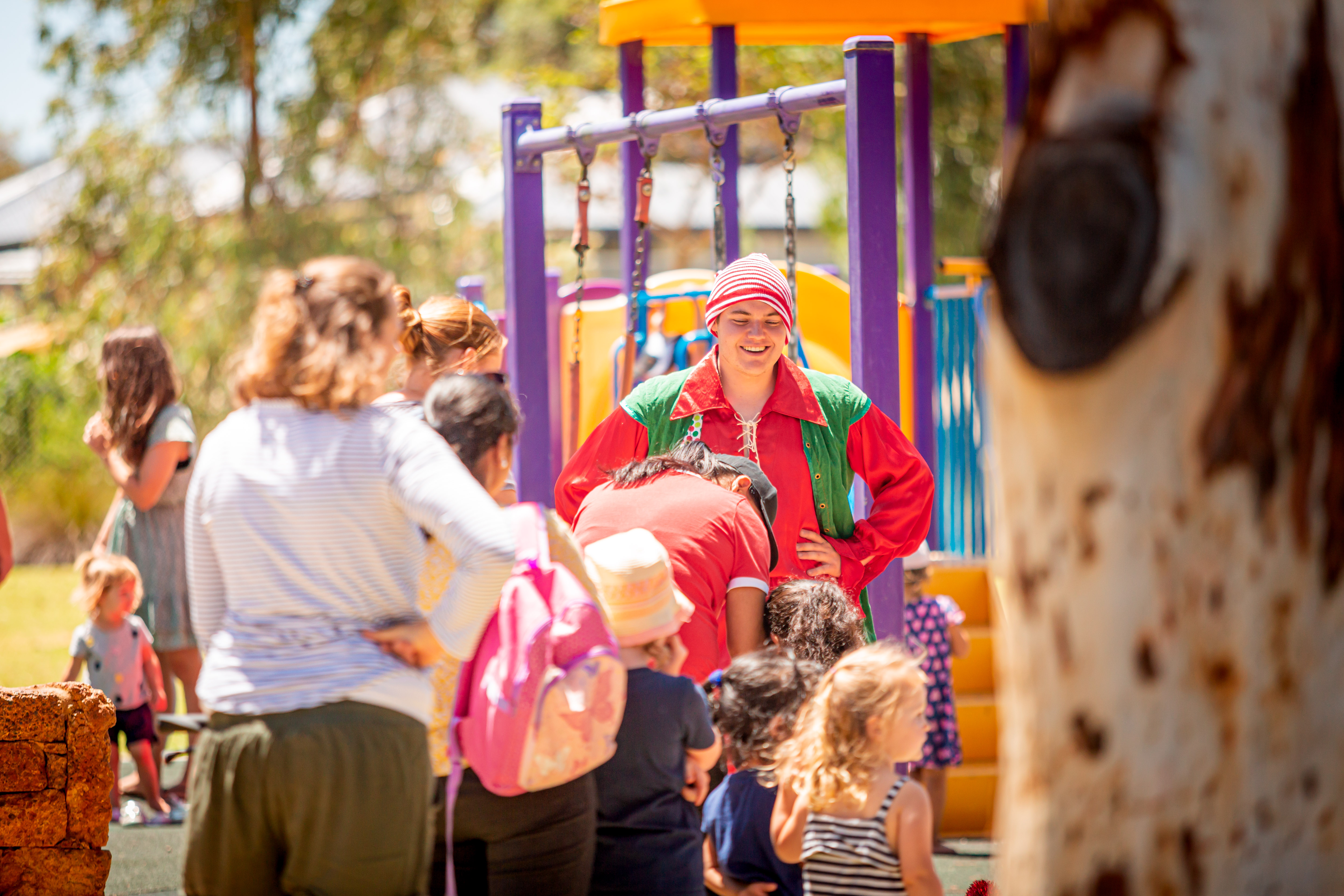 Children and families on play equipment with an Adult sized Christmas Elf